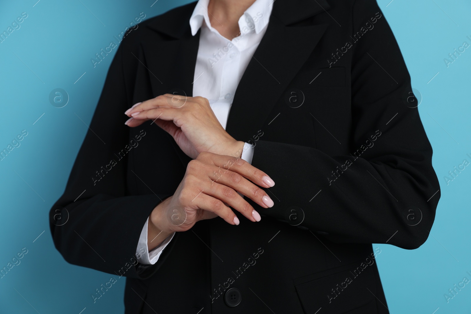 Confident business woman in suit on light blue background, closeup Photo of Confident business woman in suit on light blue background, closeup