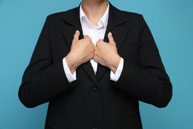 Photo of Confident business woman in suit on light blue background, closeup