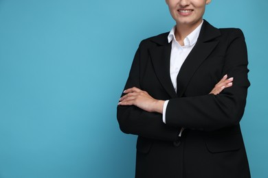 Photo of Confident business woman in suit on light blue background, closeup. Space for text