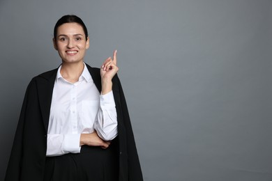 Photo of Confident business woman in suit pointing at something on grey background. Space for text
