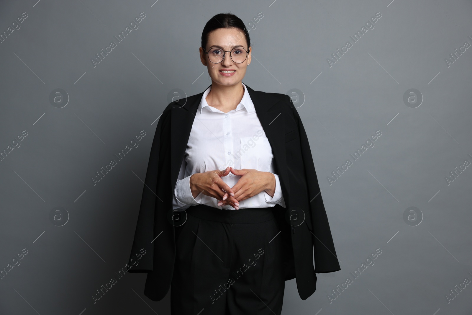 Confident business woman in suit on grey background Photo of Confident business woman in suit on grey background