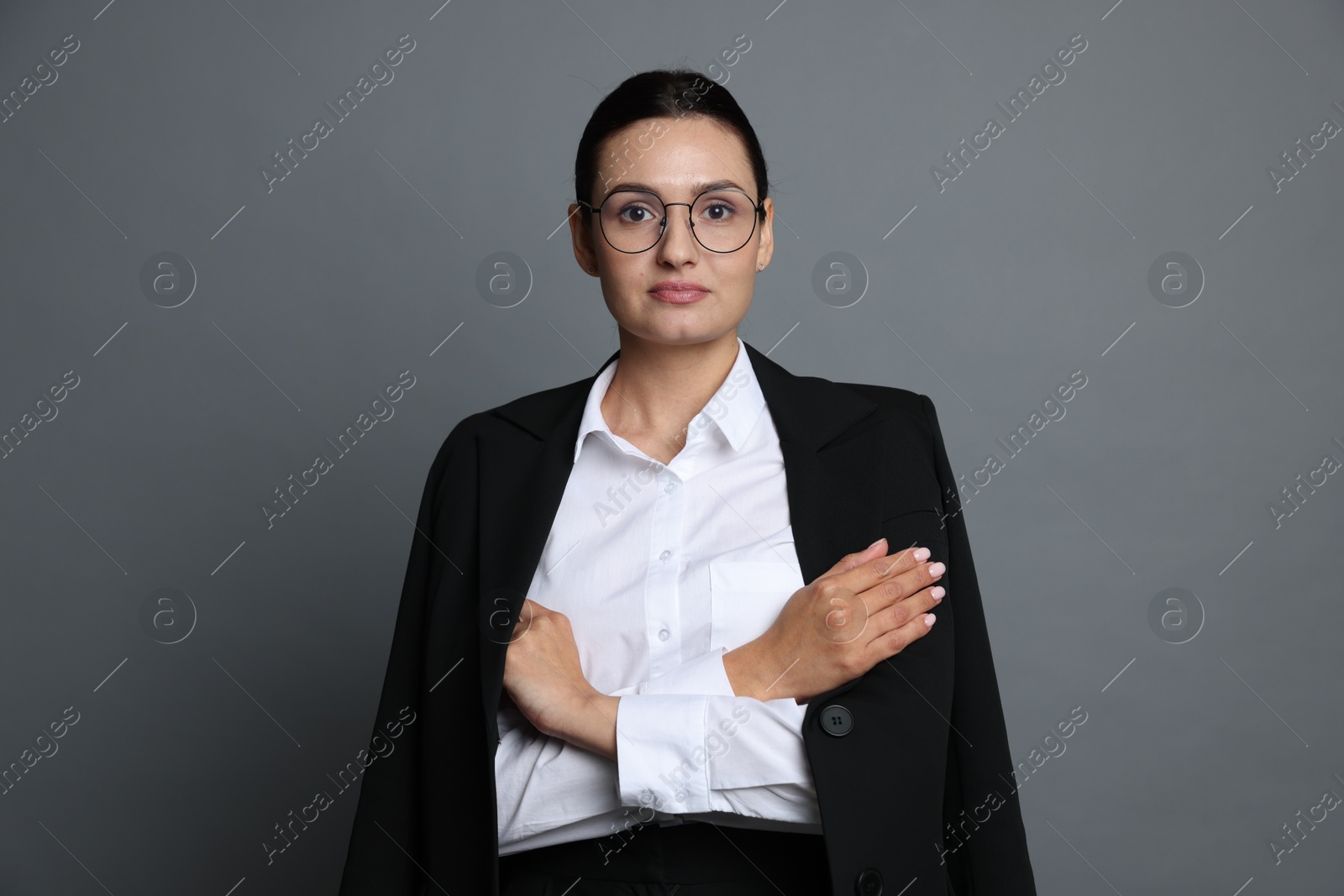 Confident business woman in suit on grey background Photo of Confident business woman in suit on grey background