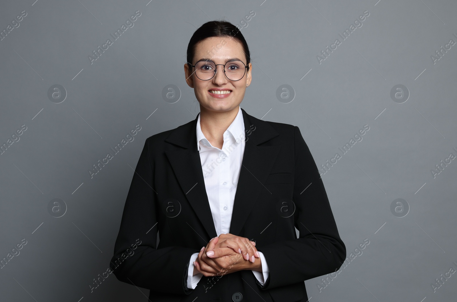 Confident business woman in suit on grey background Photo of Confident business woman in suit on grey background