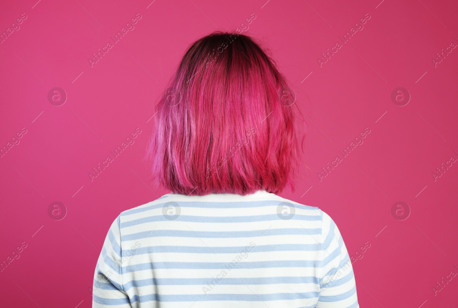 Woman with beautiful bright dyed hair on pink background, back view Photo of Woman with beautiful bright dyed hair on pink background, back view
