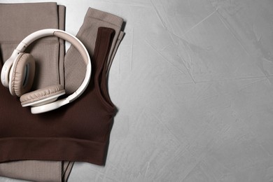 Photo of Sportswear and headphones on gray textured background, top view. Space for text