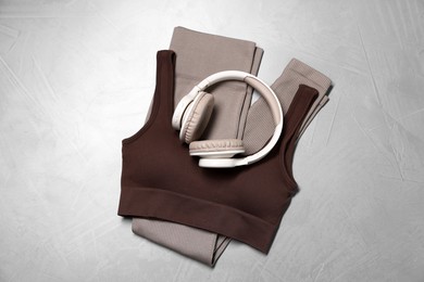 Photo of Sportswear and headphones on gray textured background, top view