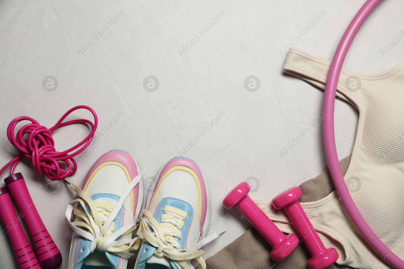 Sportswear, sneakers, hula hoop, skipping rope and dumbbells on gray textured background, flat lay. Space for text Photo of Sportswear, sneakers, hula hoop, skipping rope and dumbbells on gray textured background, flat lay. Space for text