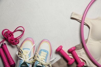 Photo of Sportswear, sneakers, hula hoop, skipping rope and dumbbells on gray textured background, flat lay. Space for text