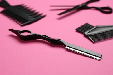 Photo of Different hairdresser's tools on pink background, closeup