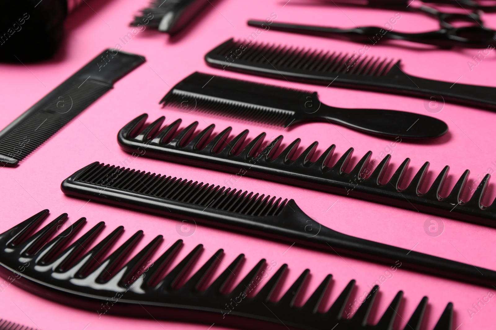 Photo of Different hairdresser's tools on pink background, closeup