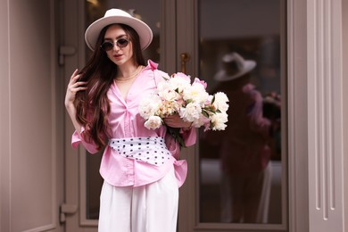 Photo of Stylish woman with bouquet of beautiful peonies outdoors