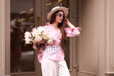 Photo of Stylish woman with bouquet of beautiful peonies outdoors