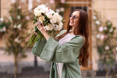 Photo of Charming woman with bouquet of beautiful peonies on city street