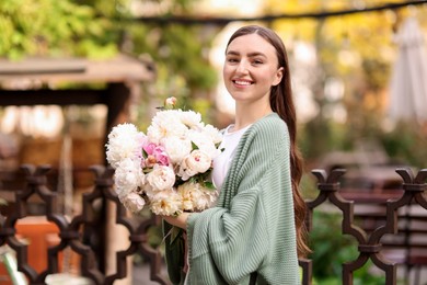 Photo of Charming woman with bouquet of beautiful peonies on city street