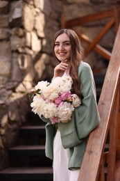 Photo of Charming woman with bouquet of beautiful peonies on city street