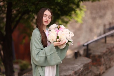 Photo of Charming woman with bouquet of beautiful peonies on city street. Space for text