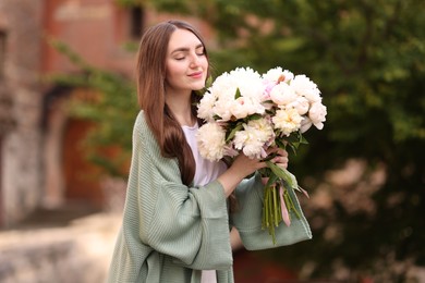 Photo of Charming woman with bouquet of beautiful peonies on city street