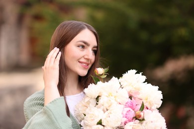 Photo of Charming woman with bouquet of beautiful peonies on city street