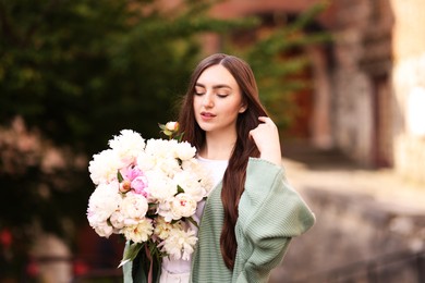 Photo of Charming woman with bouquet of beautiful peonies on city street