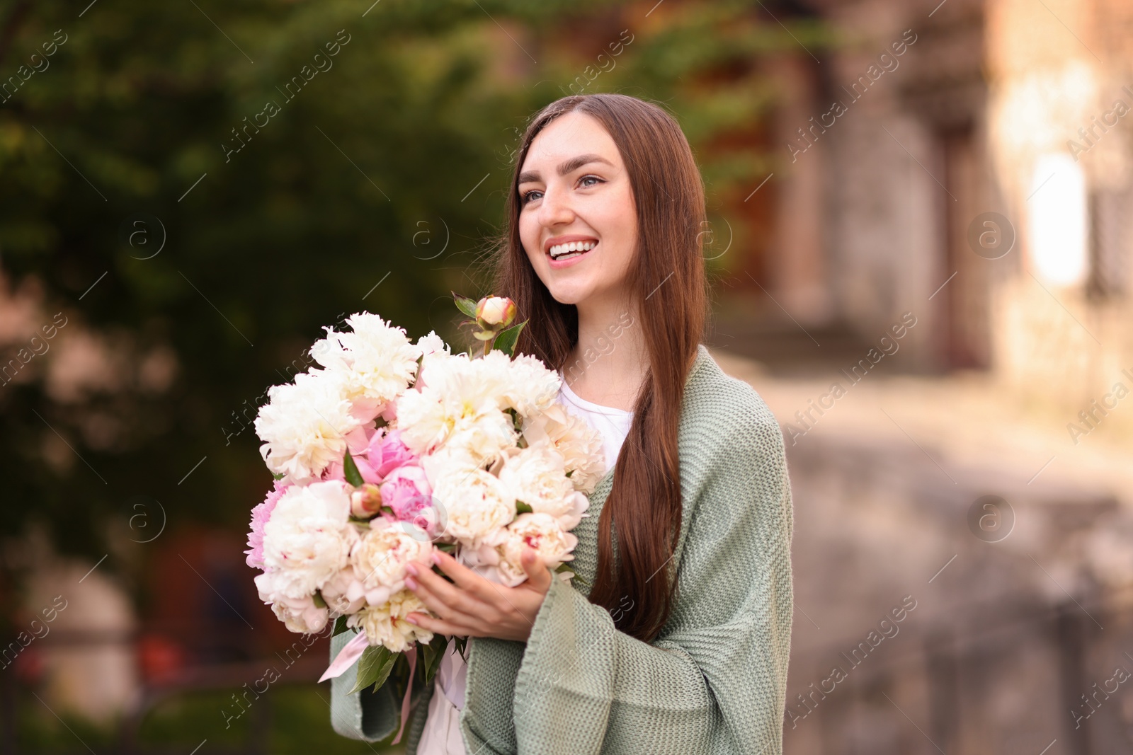 Charming woman with bouquet of beautiful peonies on city street Photo of Charming woman with bouquet of beautiful peonies on city street