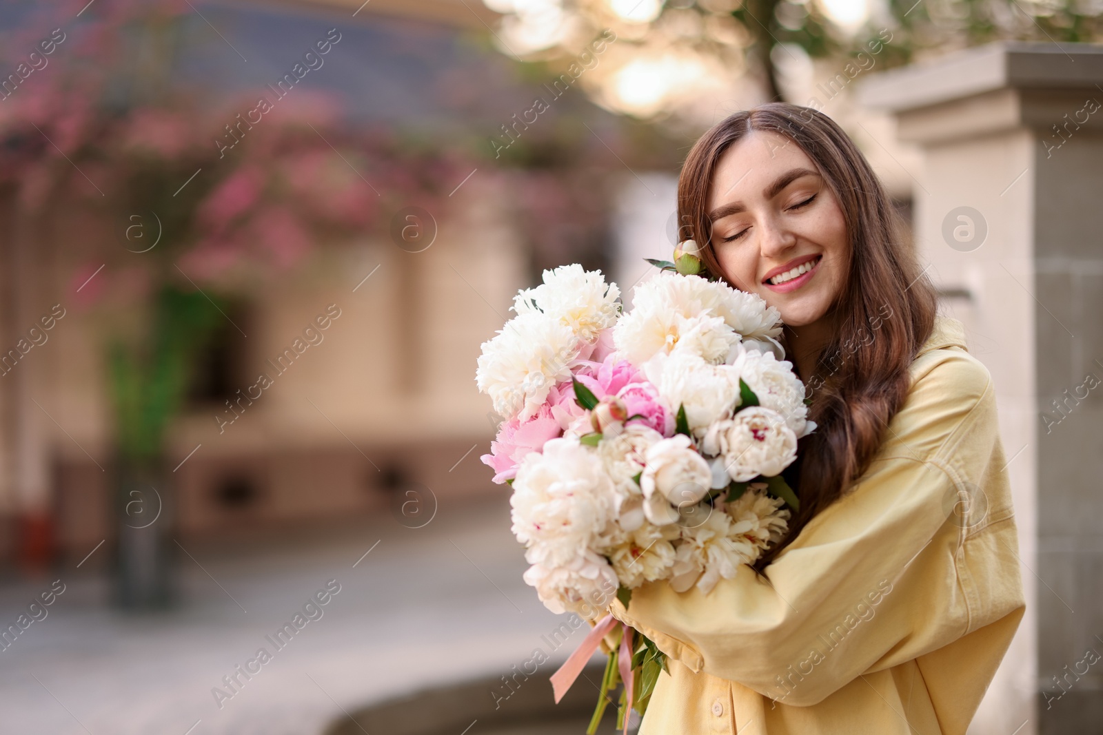 Woman with bouquet of beautiful peonies on city street. Space for text Photo of Woman with bouquet of beautiful peonies on city street. Space for text