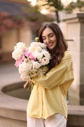 Photo of Woman with bouquet of beautiful peonies on city street
