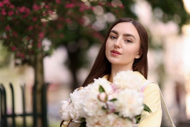 Photo of Woman with bouquet of beautiful peonies on city street. Space for text