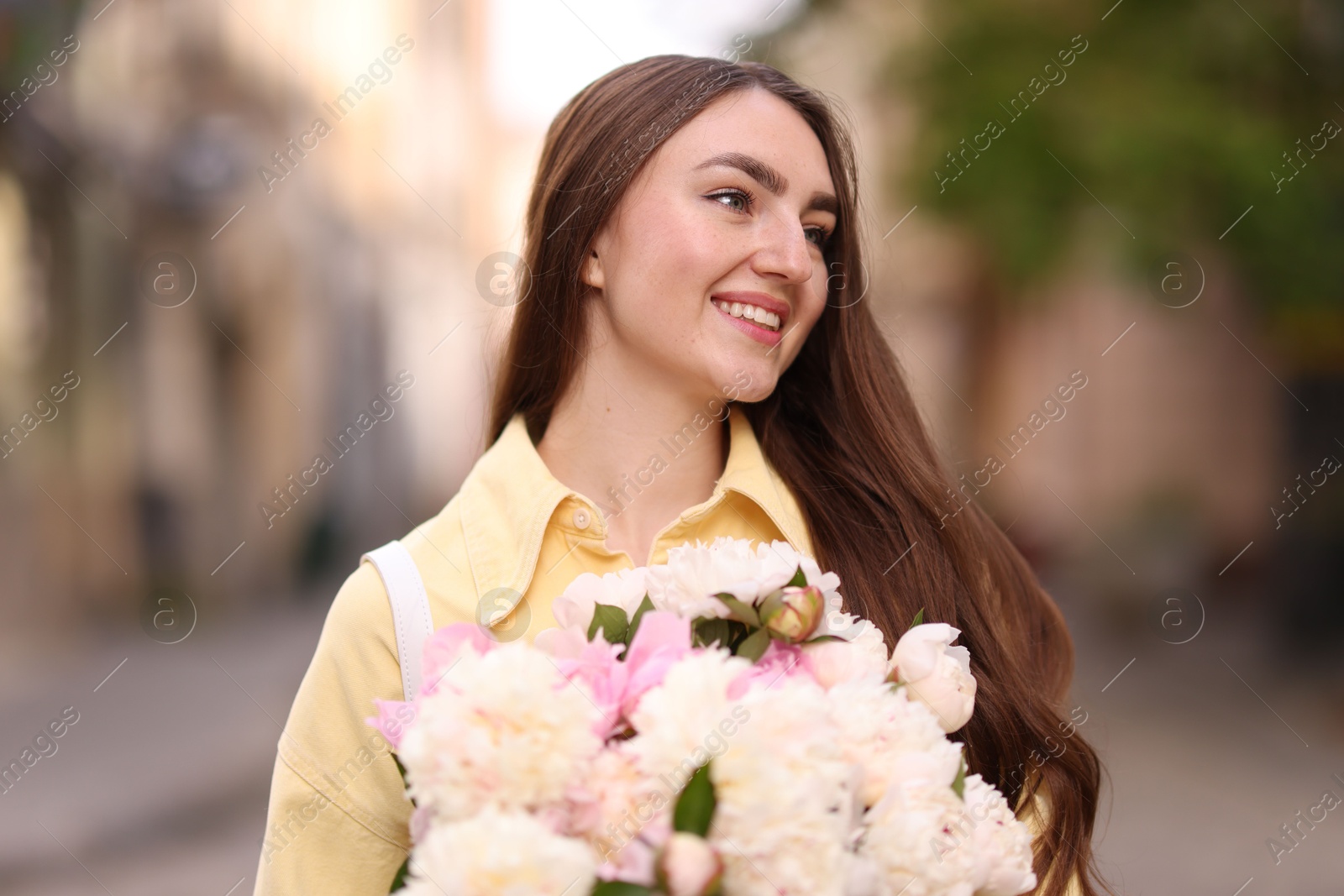 Woman with bouquet of beautiful peonies on city street Photo of Woman with bouquet of beautiful peonies on city street
