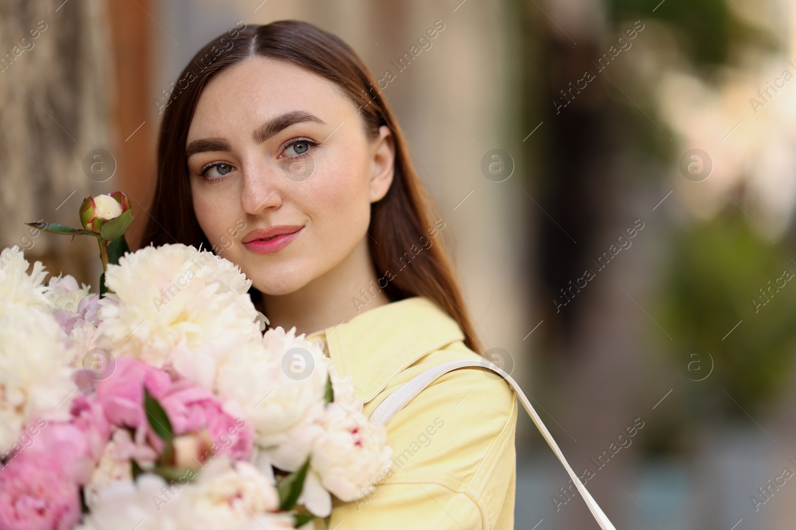 Woman with bouquet of beautiful peonies on city street. Space for text Photo of Woman with bouquet of beautiful peonies on city street. Space for text