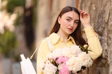 Photo of Woman with bouquet of beautiful peonies on city street
