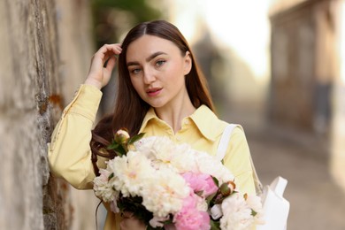 Photo of Woman with bouquet of beautiful peonies on city street