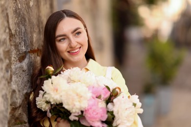 Photo of Woman with bouquet of beautiful peonies on city street