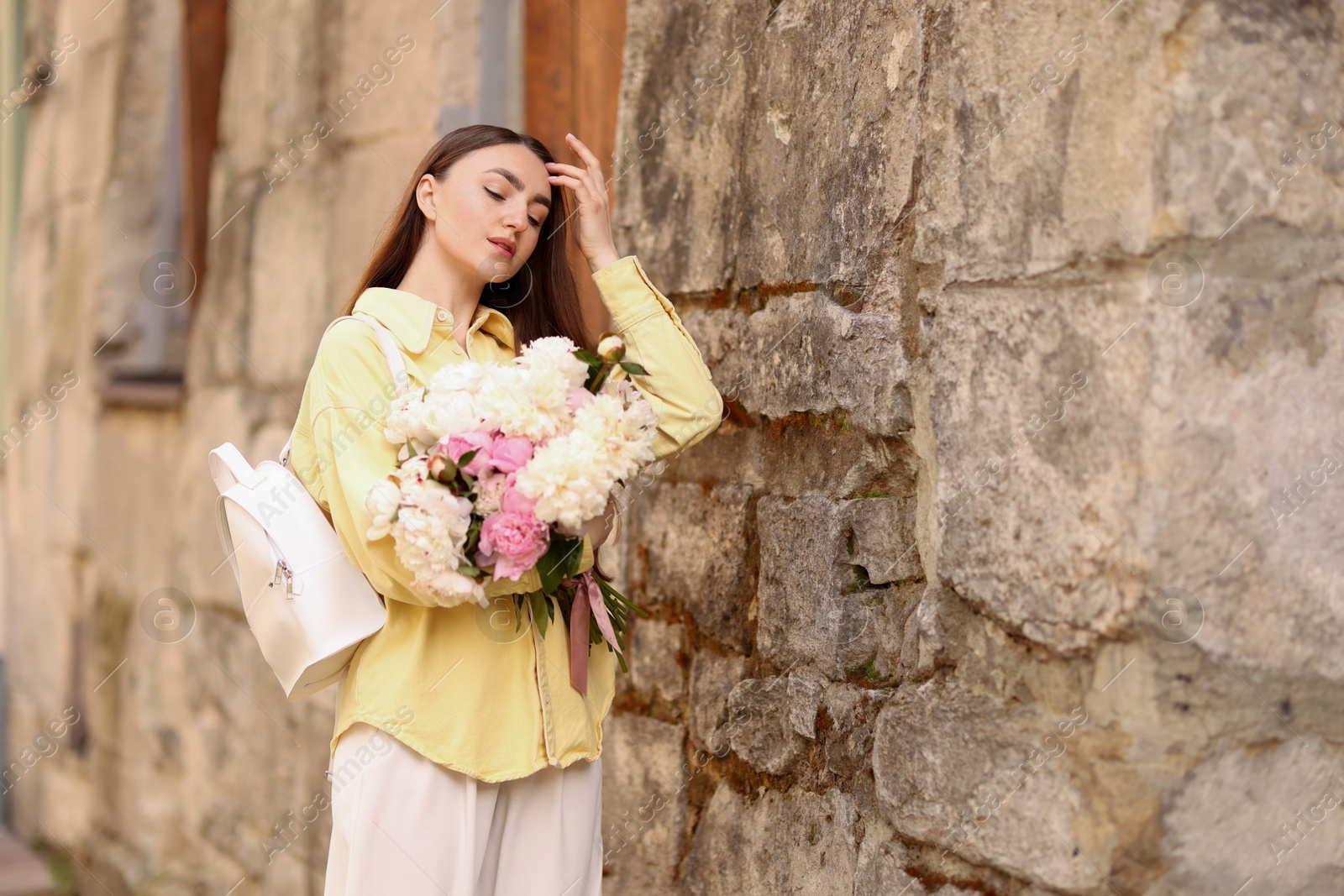 Woman with bouquet of beautiful peonies on city street. Space for text Photo of Woman with bouquet of beautiful peonies on city street. Space for text