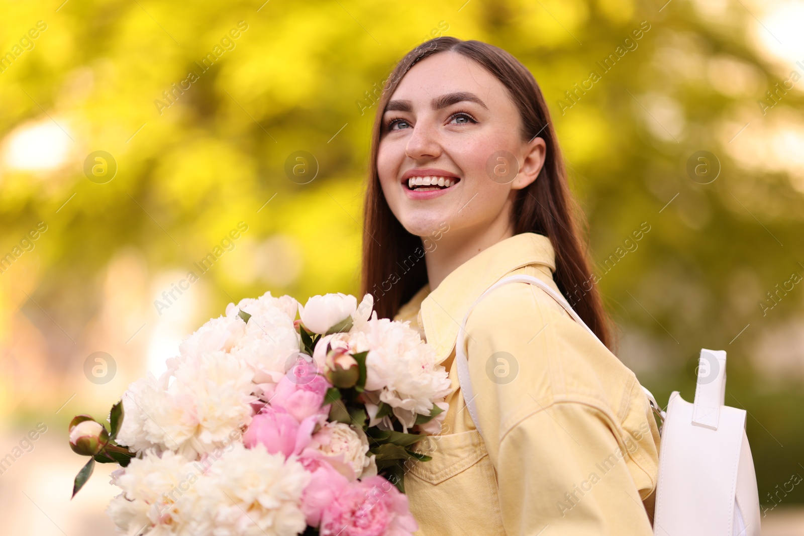 Woman with bouquet of beautiful peonies on city street Photo of Woman with bouquet of beautiful peonies on city street