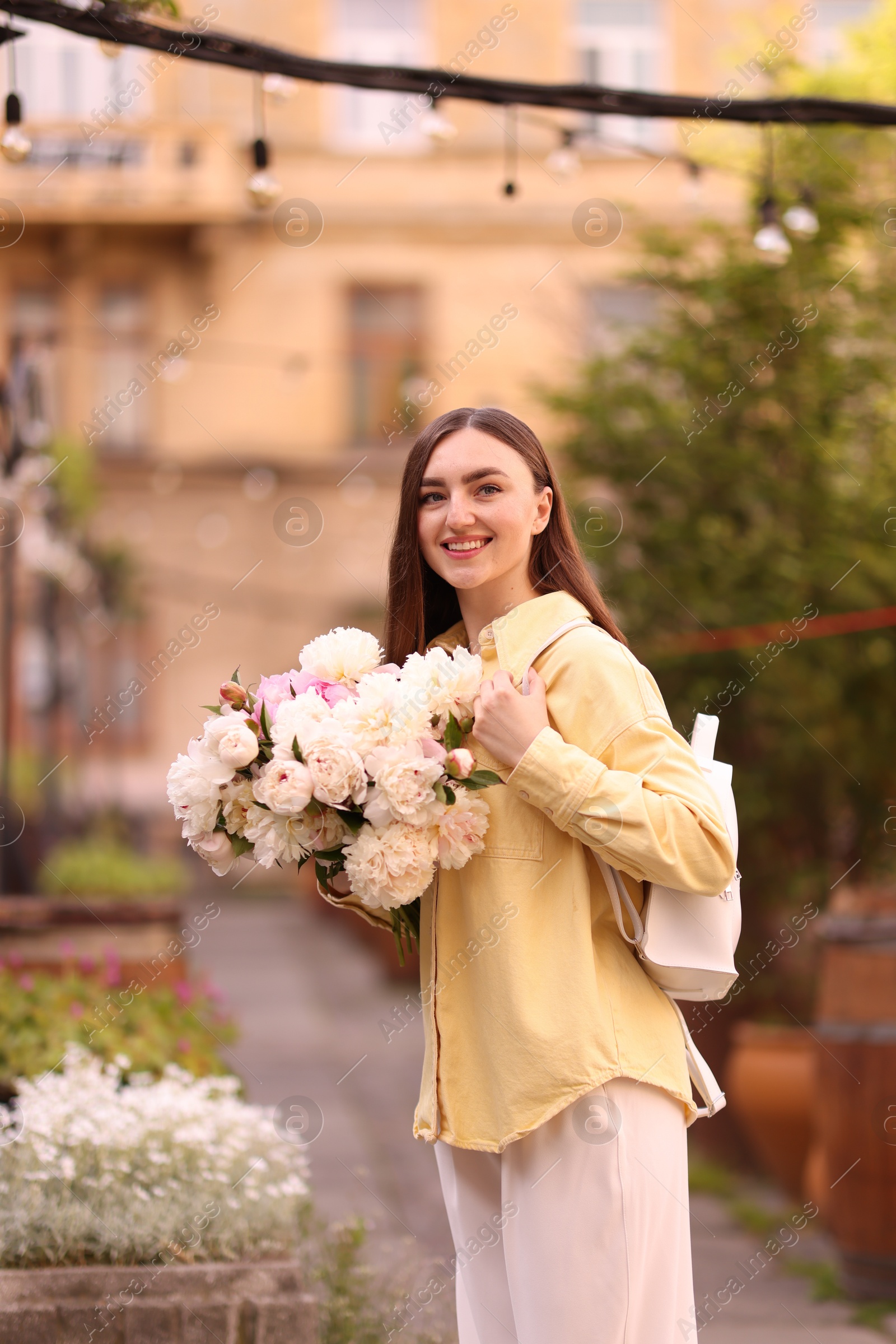 Woman with bouquet of beautiful peonies on city street Photo of Woman with bouquet of beautiful peonies on city street