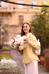 Photo of Woman with bouquet of beautiful peonies on city street
