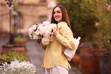 Photo of Woman with bouquet of beautiful peonies on city street