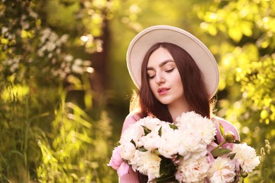 Photo of Beautiful woman with bouquet of peonies in park. Space for text