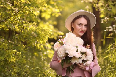 Photo of Beautiful woman with bouquet of peonies in park. Space for text