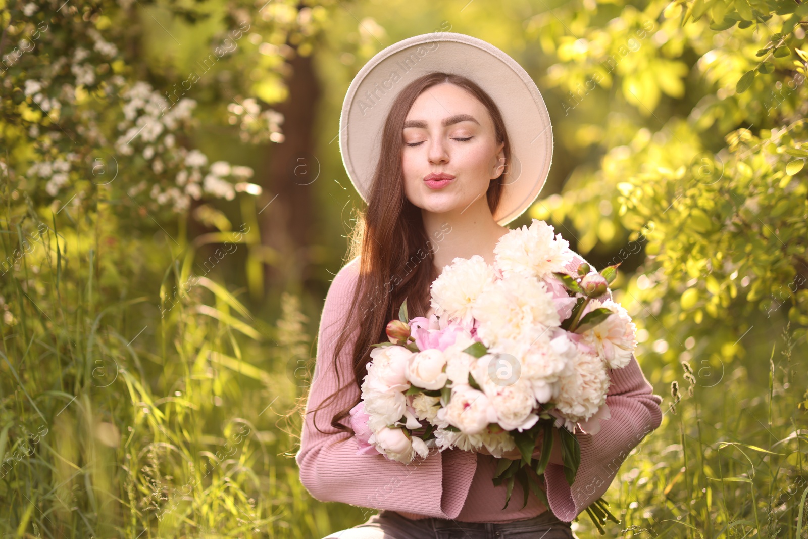 Beautiful woman with bouquet of peonies in park Photo of Beautiful woman with bouquet of peonies in park