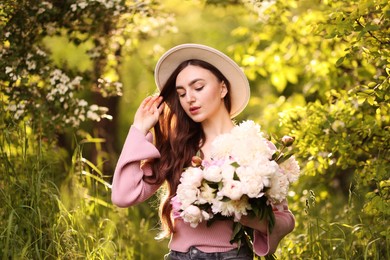 Photo of Beautiful woman with bouquet of peonies in park