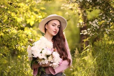 Photo of Beautiful woman with bouquet of peonies in park