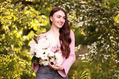 Photo of Beautiful woman with bouquet of peonies in park