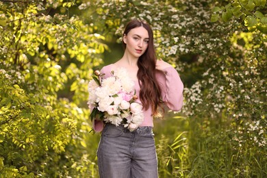 Photo of Beautiful woman with bouquet of peonies in park
