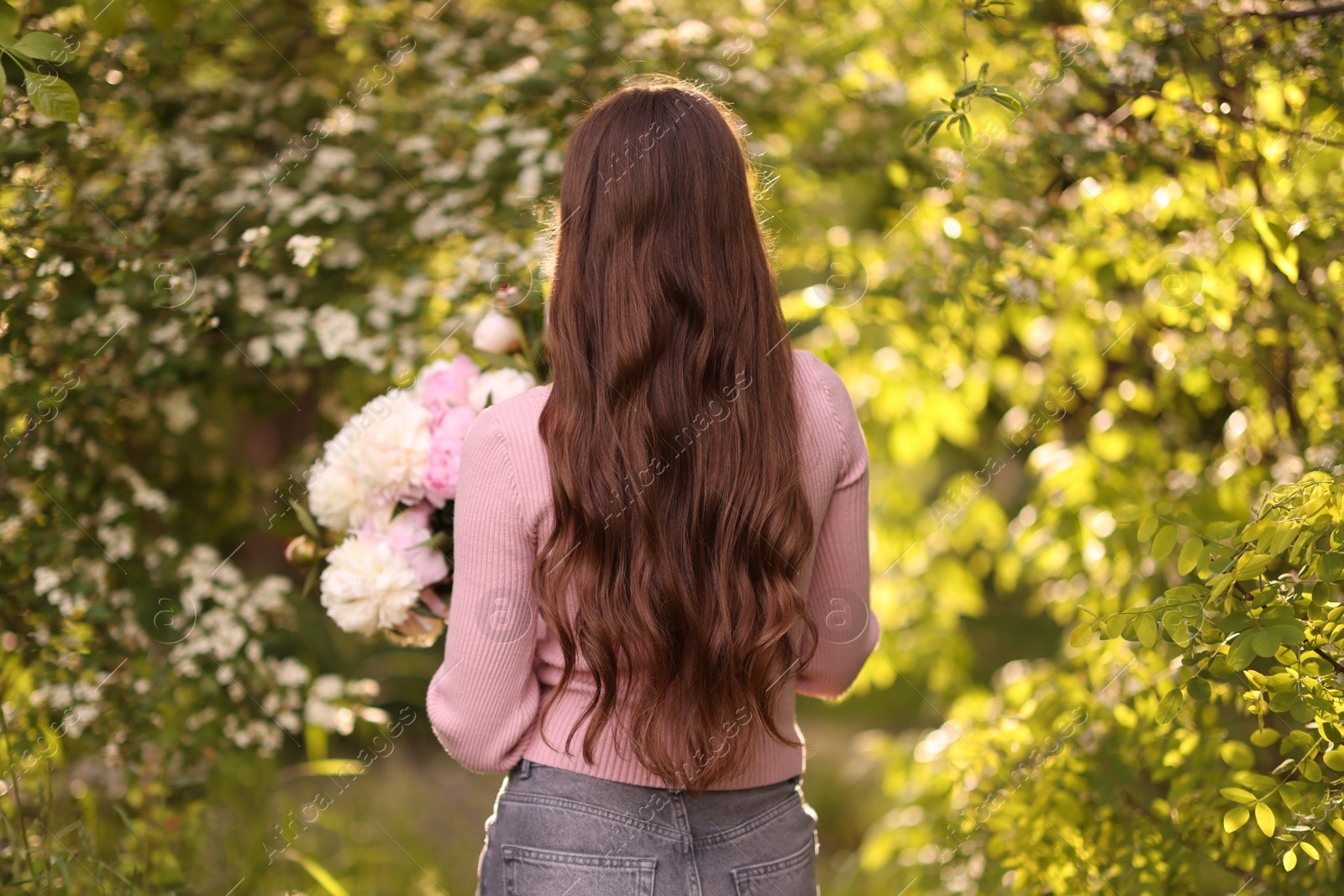Beautiful woman with bouquet of peonies in park, back view Photo of Beautiful woman with bouquet of peonies in park, back view