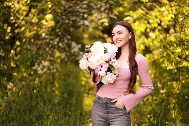 Photo of Beautiful woman with bouquet of peonies in park. Space for text