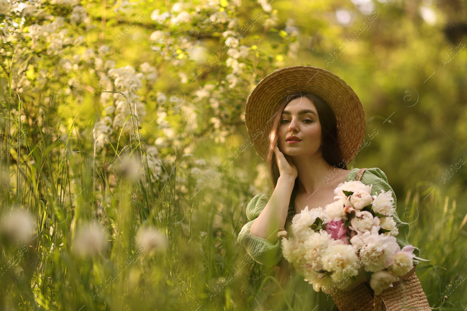 Photo of Beautiful woman with bouquet of peonies in park. Space for text