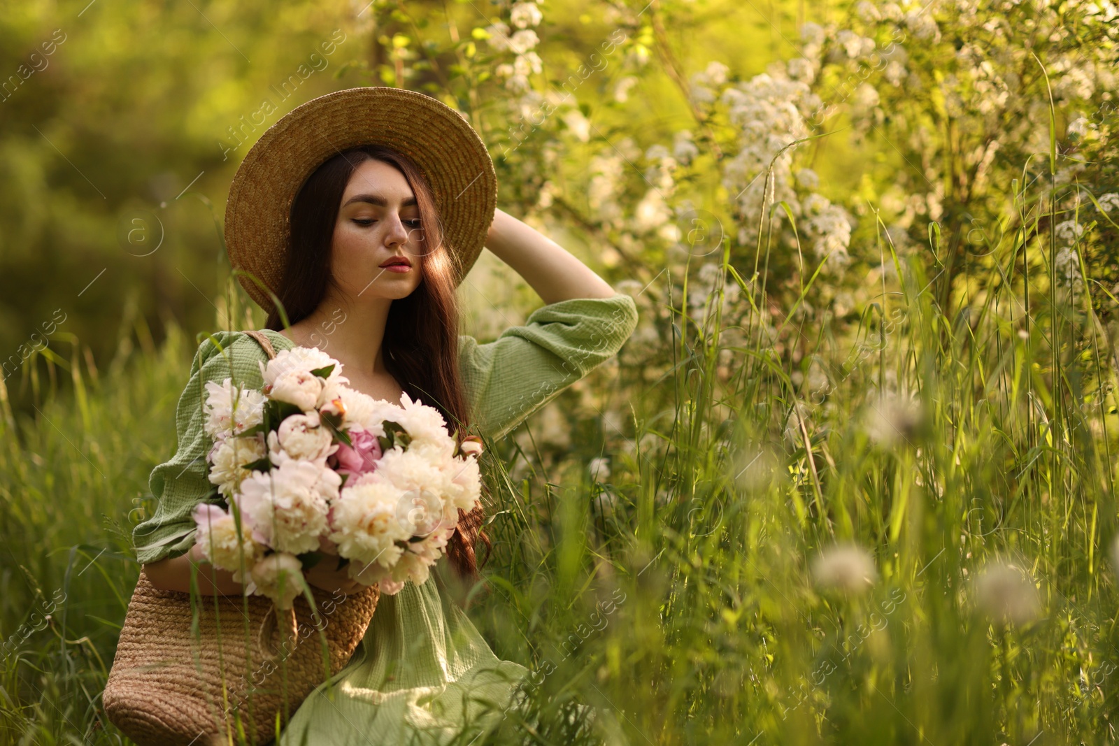 Photo of Beautiful woman with bouquet of peonies in park. Space for text