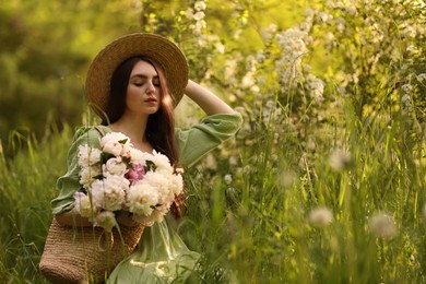 Photo of Beautiful woman with bouquet of peonies in park. Space for text