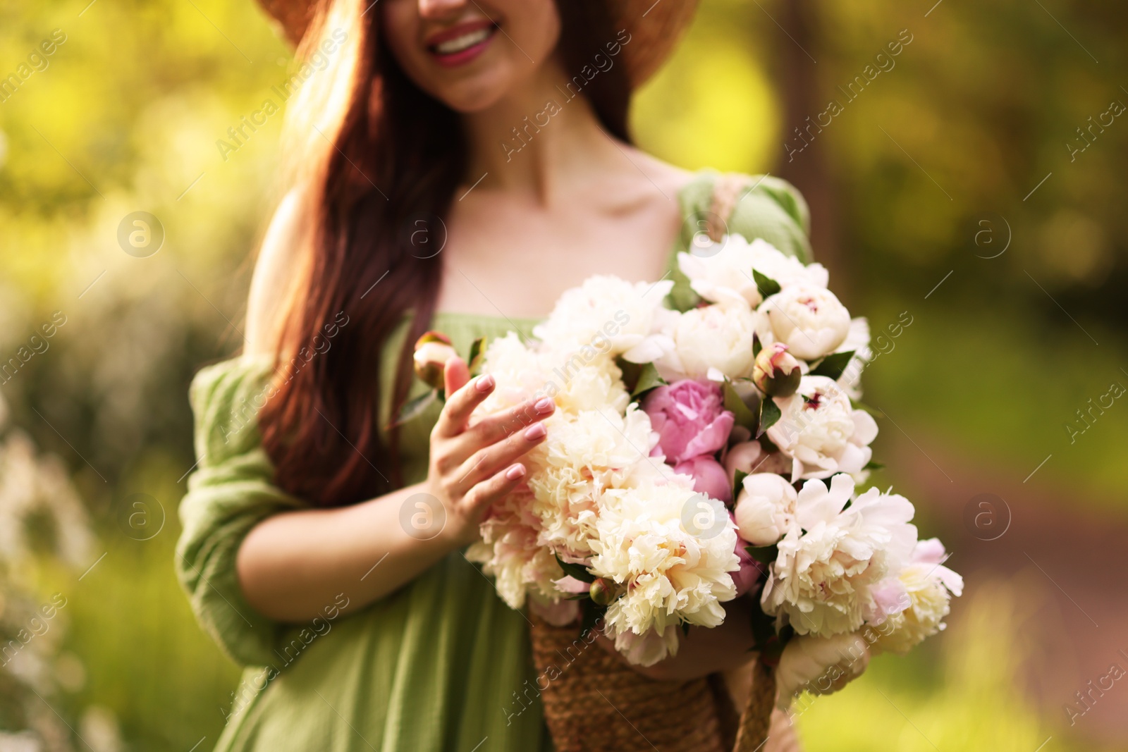 Photo of Beautiful woman with bouquet of peonies in park, closeup